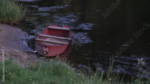 The red boat near the streaming river at the sunset photo