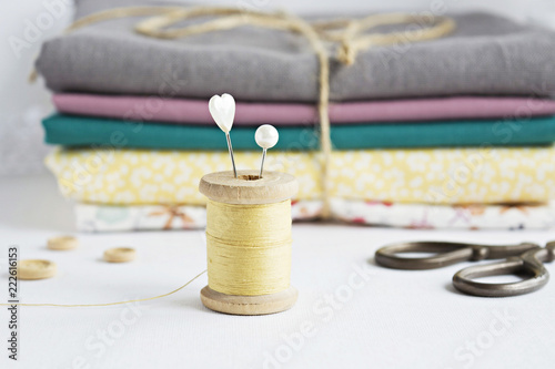 Vintage yellow thread spool , pins, retro scissors and cotton fabrics