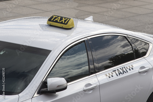 A taxi sign on a white car.