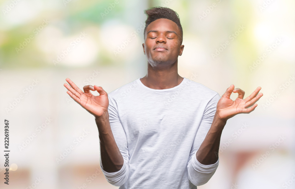 Young african american man over isolated background relax and smiling with eyes closed doing meditation gesture with fingers. Yoga concept. Young african american man over isolated background relax and smiling with eyes closed doing meditation gesture with fingers. Yoga concept.
