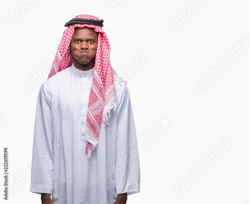 Young arabic african man wearing traditional keffiyeh over isolated background puffing cheeks with funny face. Mouth inflated with air, crazy expression.