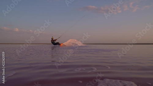 A man in a helmet is engaged in kitesurfing, and performs a trick with a camera jumping over photo