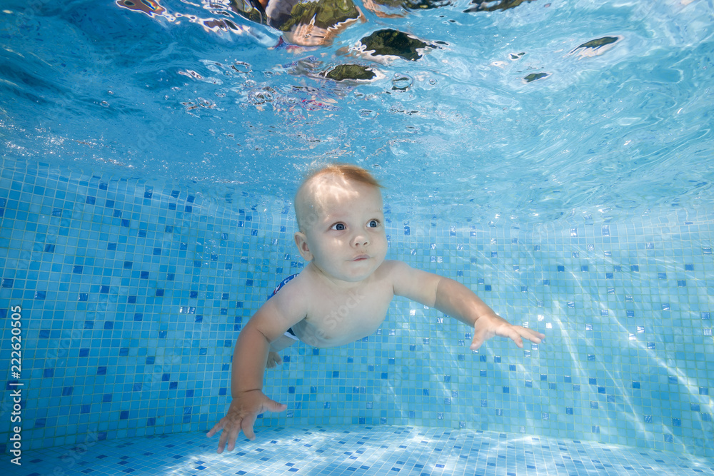 Little boy dives underwater in the pool