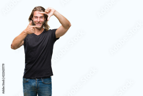 Young handsome man with long hair over isolated background smiling making frame with hands and fingers with happy face. Creativity and photography concept. © Krakenimages.com