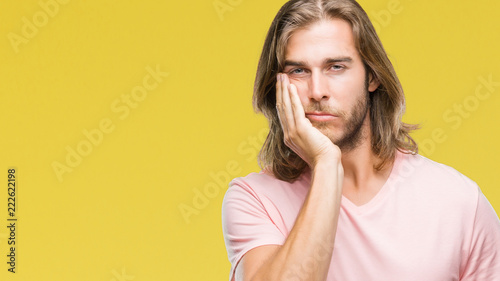 Young handsome man with long hair over isolated background thinking looking tired and bored with depression problems with crossed arms.