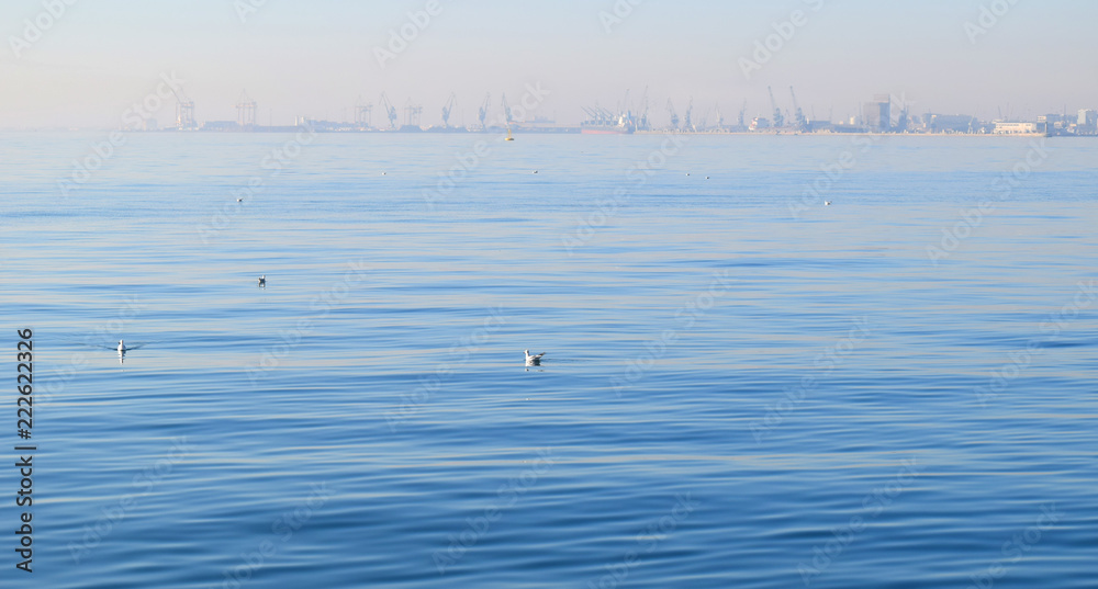 Fototapeta Calm blue sea at Thessaloniki seafront. Old harbour background in the mist.