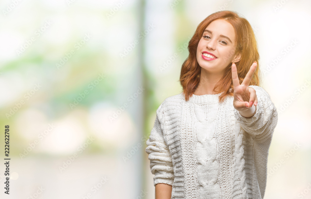 Young beautiful woman over isolated background wearing winter sweater showing and pointing up with fingers number two while smiling confident and happy.