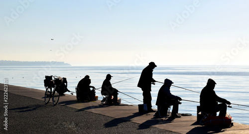 Silhouettes of fishermen in Thessaloniki seafront, Greece. Winter foggy seascape. 