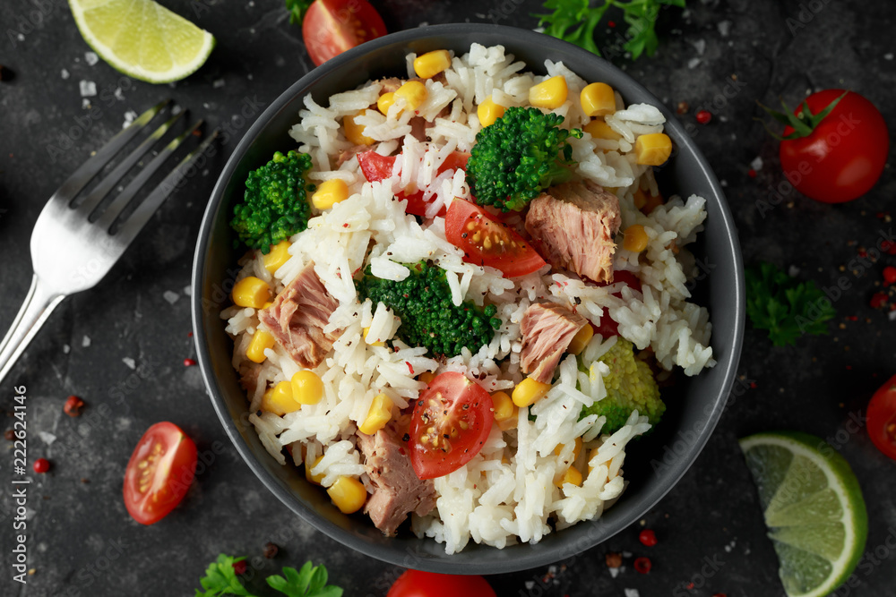 Fresh Tuna rice salad with sweet corn, cherry tomatoes, broccoli, parsley and lime in black bowl