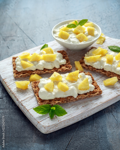 Homemade Crispbread toast with Cottage Cheese and Pineapple on white wooden board.