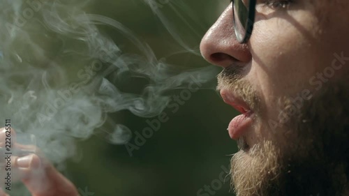Man smoking a rolled up cigarette. Close up shot of man's hand and mouth. Man smoking a joint with marijuana