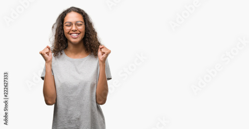 Beautiful young hispanic woman wearing glasses excited for success with arms raised celebrating victory smiling. Winner concept. © Krakenimages.com