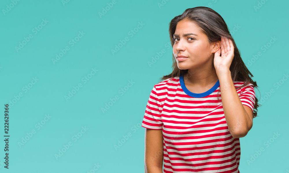 Young beautiful arab woman over isolated background smiling with hand over ear listening an hearing to rumor or gossip. Deafness concept.