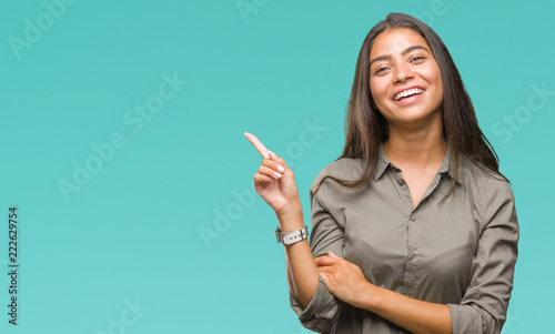 Young beautiful arab woman over isolated background with a big smile on face, pointing with hand and finger to the side looking at the camera. photo