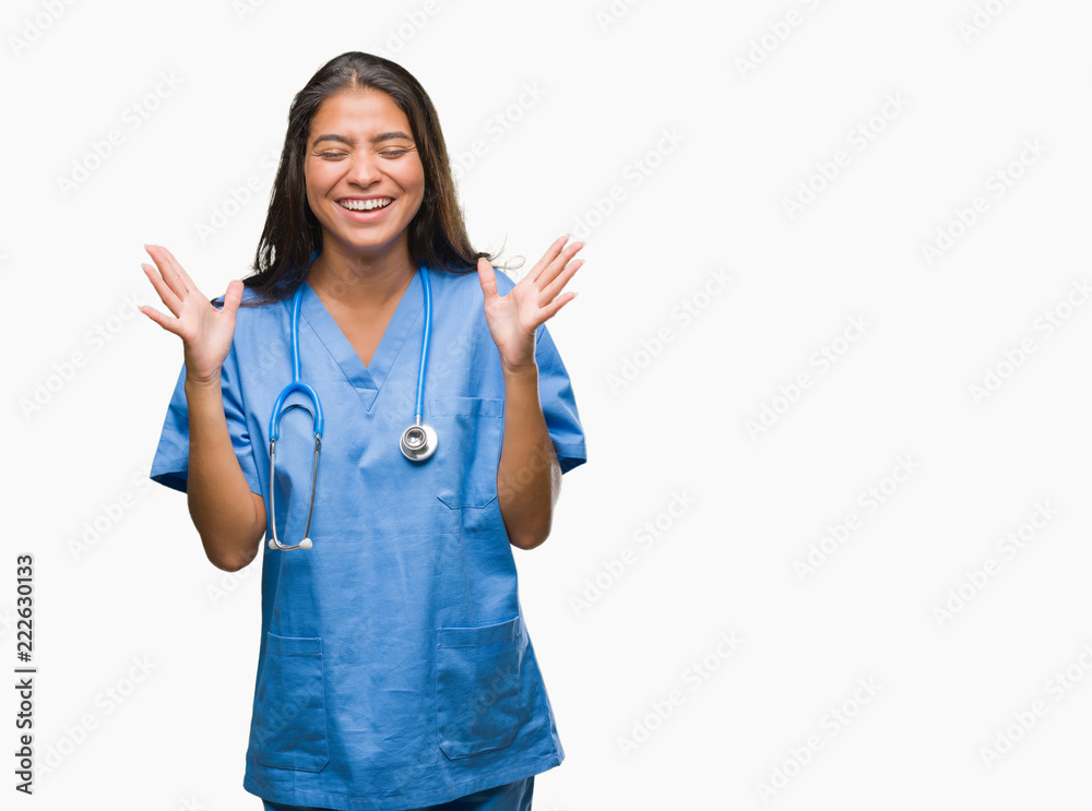 Young arab doctor surgeon woman over isolated background celebrating mad and crazy for success with arms raised and closed eyes screaming excited. Winner concept Young arab doctor surgeon woman over isolated background celebrating mad and crazy for success with arms raised and closed eyes screaming excited. Winner concept