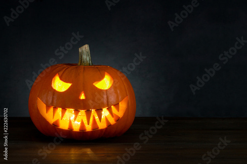 Halloween background. Pumpkin Jack O'Lantern head with candle light with copy space on dark background