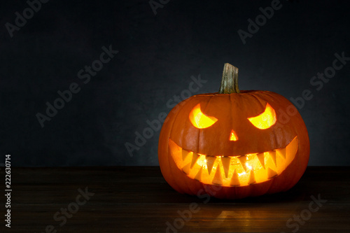 Halloween background. Pumpkin Jack O'Lantern head with candle light with copy space on dark background