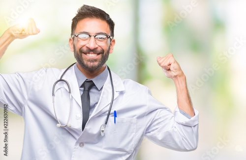 Adult hispanic doctor man over isolated background showing arms muscles smiling proud. Fitness concept.