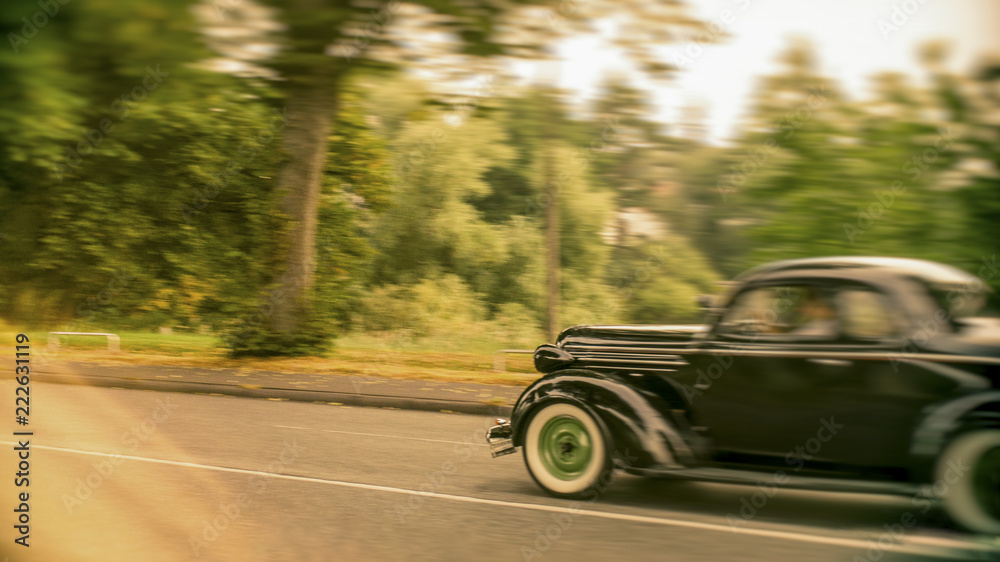 Old classic car driving fast on a vintage car rally blurred background and the car is out of focus