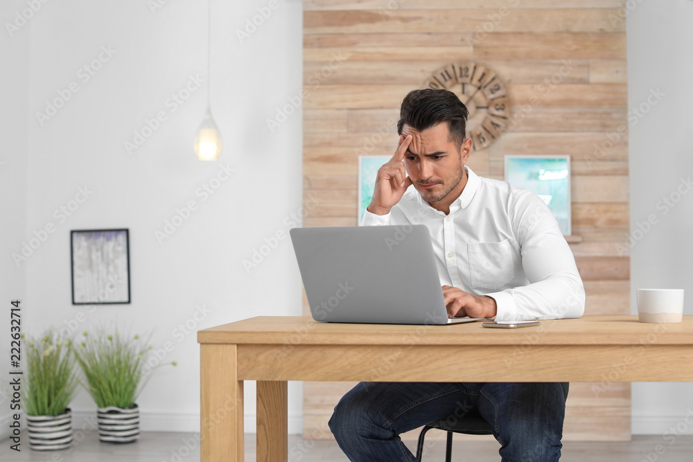Portrait of handsome young man with laptop in office Portrait of handsome young man with laptop in office