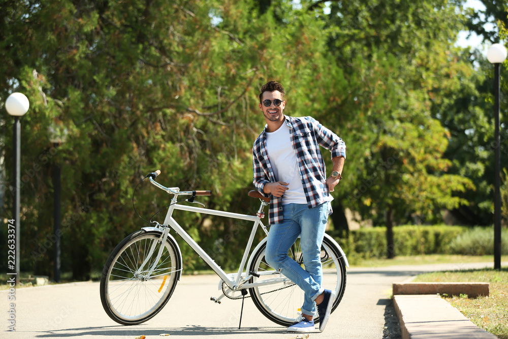 Handsome young hipster man with bicycle in park Handsome young hipster man with bicycle in park