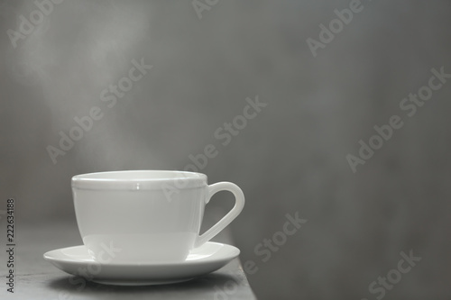 Cup of tea and saucer on table against gray background