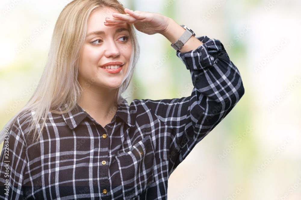 Young blonde woman over isolated background very happy and smiling looking far away with hand over head. Searching concept.