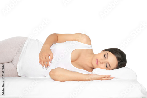Beautiful pregnant woman sleeping with orthopedic pillow on bed against white background