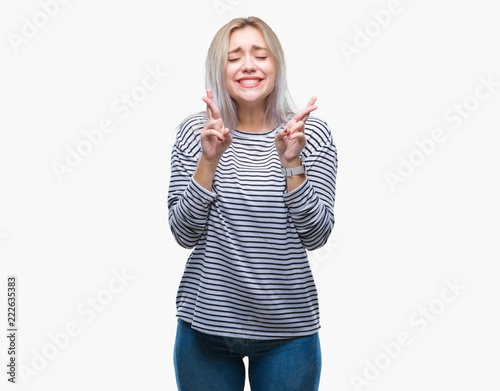 Young blonde woman over isolated background smiling crossing fingers with hope and eyes closed. Luck and superstitious concept.