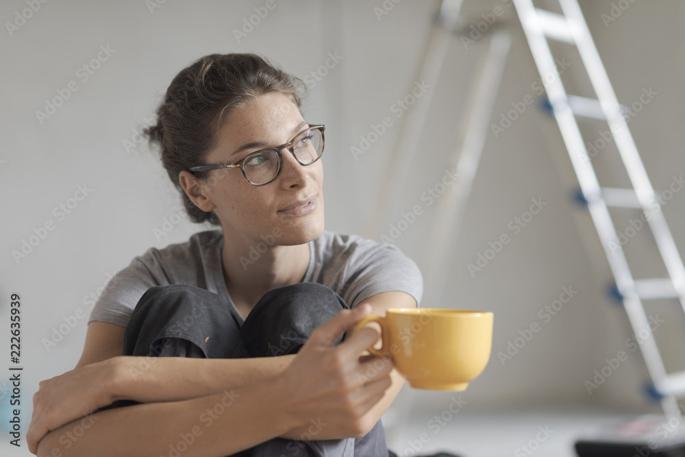 Woman doing a home renovation and having a coffee break Woman doing a home renovation and having a coffee break