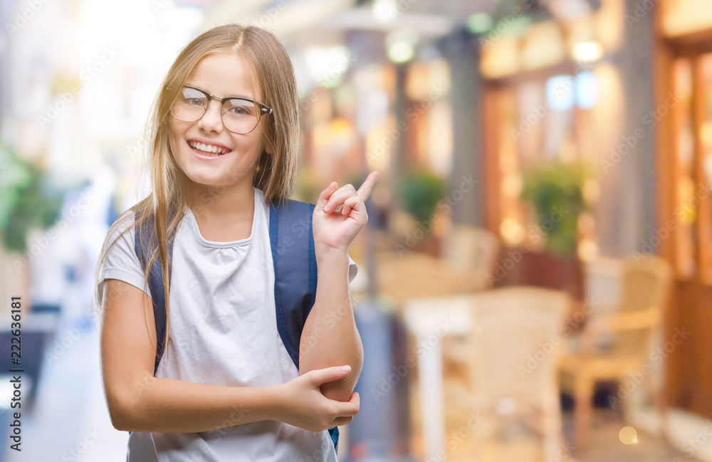 Young beautiful smart student girl wearing backpack over isolated background with a big smile on face, pointing with hand and finger to the side looking at the camera.