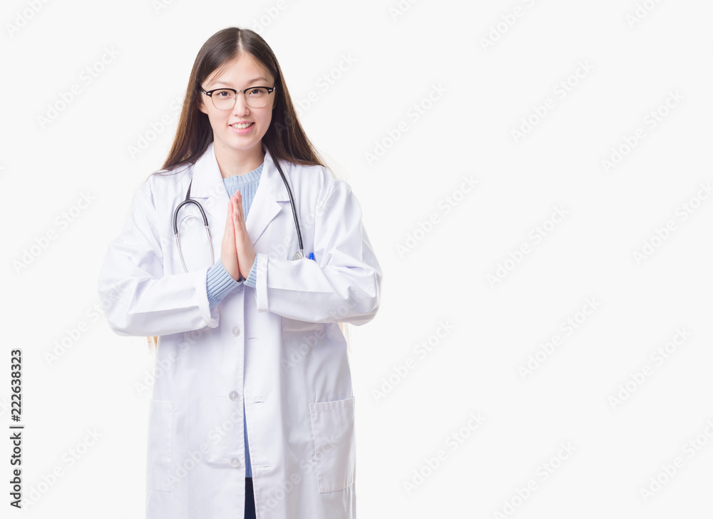 Young Chinese doctor woman over isolated background praying with hands together asking for forgiveness smiling confident. Young Chinese doctor woman over isolated background praying with hands together asking for forgiveness smiling confident.