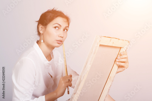 Young woman in white dress sitting on the floor begins to draw a picture. Toned