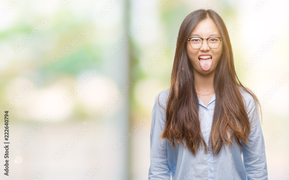 Young asian business woman wearing glasses over isolated background sticking tongue out happy with funny expression. Emotion concept. Young asian business woman wearing glasses over isolated background sticking tongue out happy with funny expression. Emotion concept.