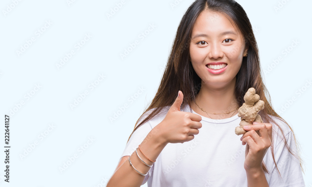 Young asian woman holding fresh organic over isolated background happy with big smile doing ok sign, thumb up with fingers, excellent sign Young asian woman holding fresh organic over isolated background happy with big smile doing ok sign, thumb up with fingers, excellent sign