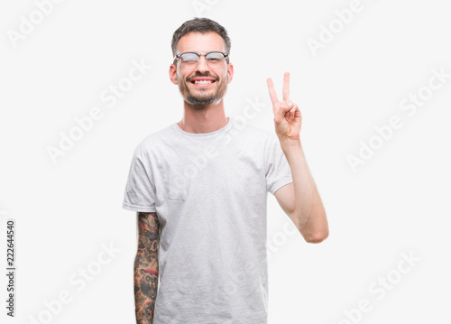 Young tattooed adult man showing and pointing up with fingers number two while smiling confident and happy.