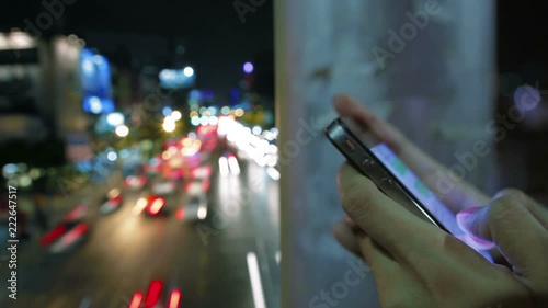 woman use smartphone touch screen texting chat close up shot urban night traffic vehicle light trail long exposure time lapse fast speed in the background