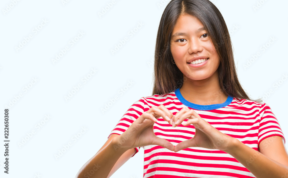 Young asian woman over isolated background smiling in love showing heart symbol and shape with hands. Romantic concept. Young asian woman over isolated background smiling in love showing heart symbol and shape with hands. Romantic concept.