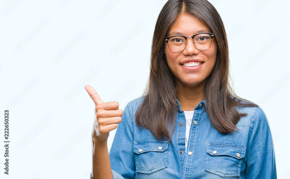 Young asian woman wearing glasses over isolated background doing happy thumbs up gesture with hand. Approving expression looking at the camera with showing success. Young asian woman wearing glasses over isolated background doing happy thumbs up gesture with hand. Approving expression looking at the camera with showing success.