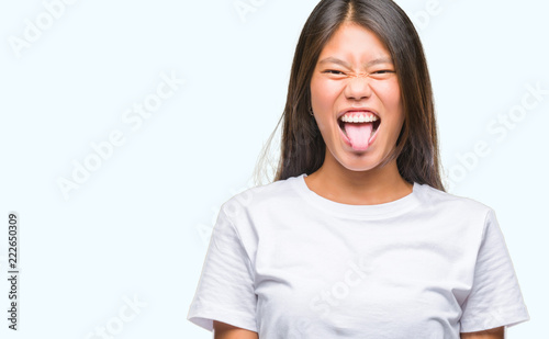 Young asian woman over isolated background sticking tongue out happy with funny expression. Emotion concept. © Krakenimages.com