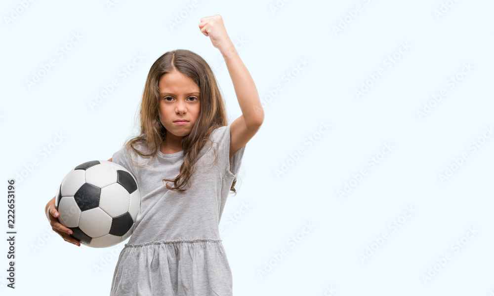 Brunette hispanic girl holding soccer football ball annoyed and frustrated shouting with anger, crazy and yelling with raised hand, anger concept