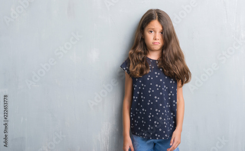 Photography Young hispanic kid over grunge grey wall skeptic and nervous, frowning upset because of problem