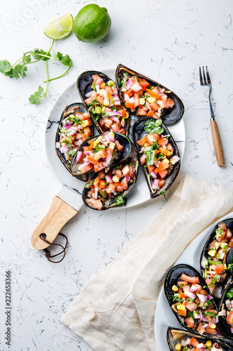 PERUVIAN FOOD. Choros a la chalaca. Big mussels, choros zapatos seasoned with purple onion, tomatoes, corn and lemon. Top view, white background. Traditional peruvian dish