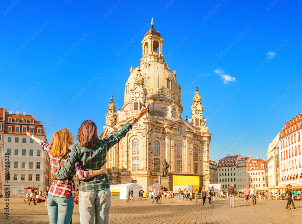 Two happy women hugging and looking at the main attraction of Dresden - Frauenkirche - obrazy, fototapety, plakaty 