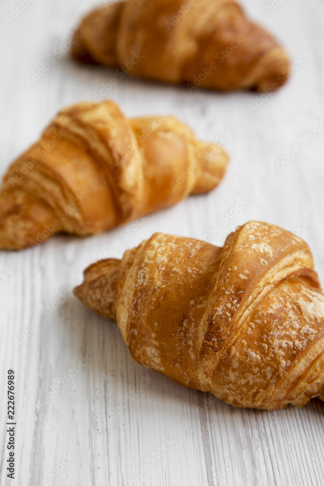 Fresh croissants on white wooden background, low angle view. Close-up. Selective focus.