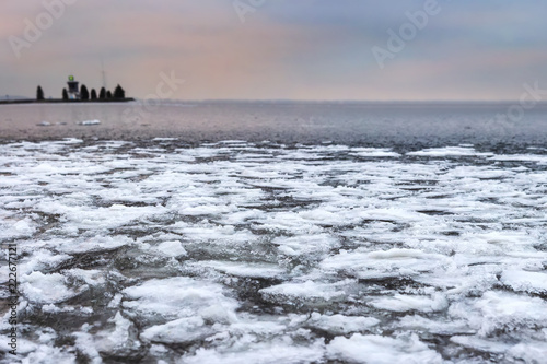 Winter landscape of icy lake with textured broken ice pieces. Frosty nature in Christmas time