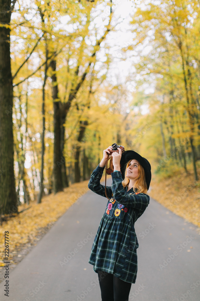 Hippie girl with old camera in a hat walks autumn park. Hippie girl with old camera in a hat walks autumn park.