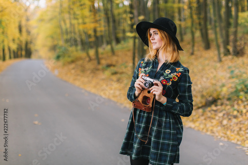 Hippie girl with old camera in a hat walks autumn park. © anatoliycherkas