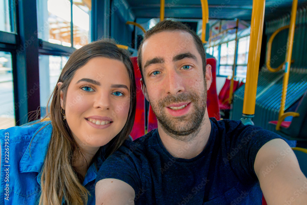 Obraz premium Happy couple taking a selfie with smartphone or camera inside a city bus