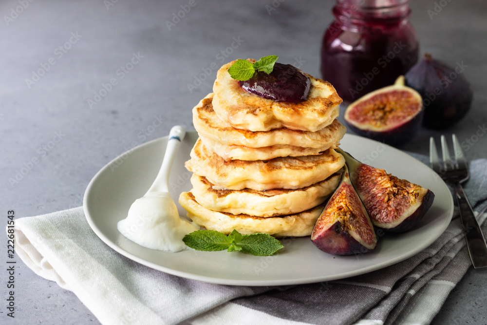Homemade fluffy pancake with fig jam and fruits decorated with mint and natural yogurt in spoon Homemade fluffy pancake with fig jam and fruits decorated with mint and natural yogurt in spoon